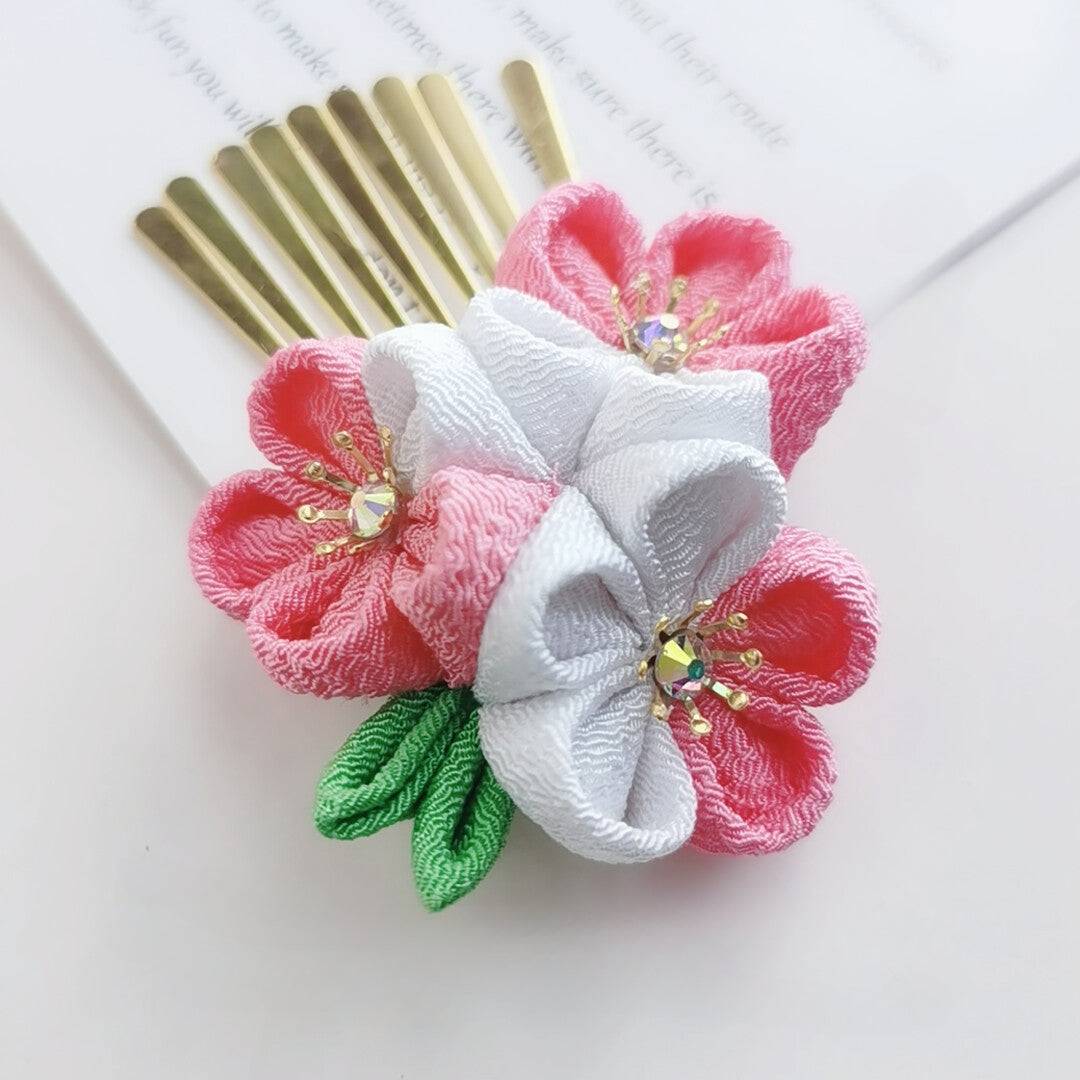 Close-up of comb hairpin with white and pink cherry blossoms and rhinestones, part of Japanese headdress set.