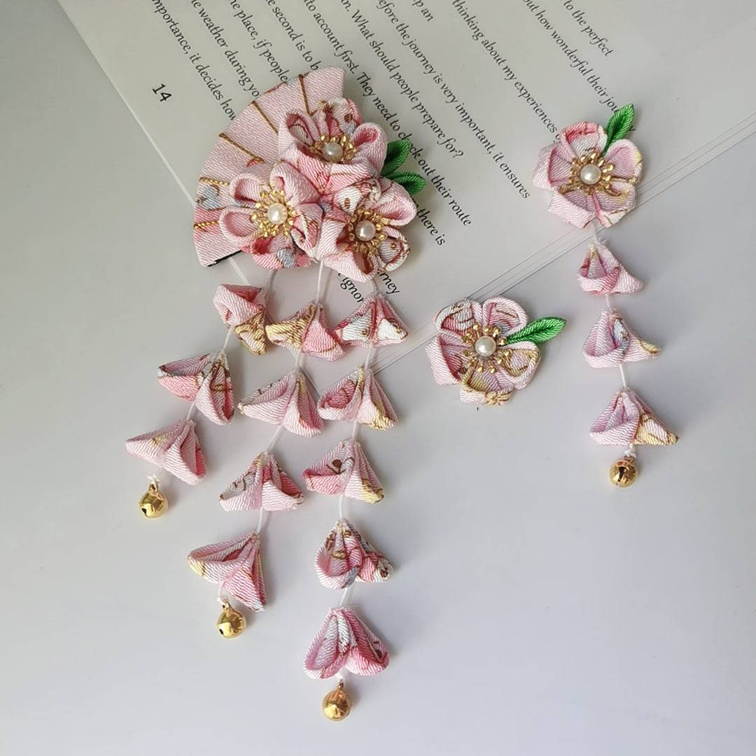 Pink kimono hair accessory set with five-petal flowers, fan design, and hanging tassels with gold bells for traditional Japanese wear.