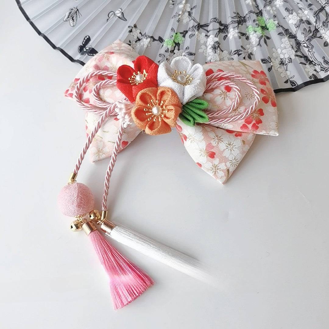 Cream and orange Japanese kimono hair accessory with cherry blossom flowers, fine bow work, and pink-white tassel detail.