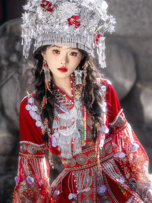 Close-up of embroidered red Miao performance dress with detailed silver jewelry and pearl accents, showcasing cultural craftsmanship.