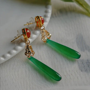 New Chinese style green agate earrings with red studs and ornate gold connectors, designed for cheongsam or Hanfu ensembles.