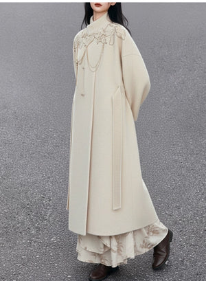 Long beige coat with floral embroidery on a plain background