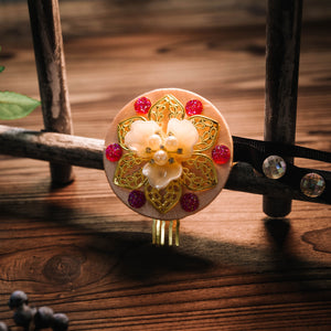 Korean hair accessories with golden floral motif and pink gem accents, showcasing traditional ethnic headgear craftsmanship.