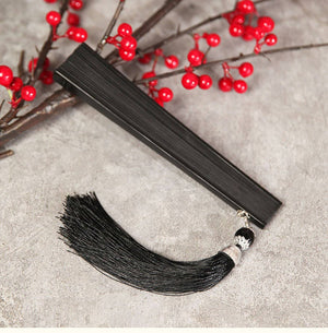 Compact black bamboo fan with black tassel, folded for easy storage. Ideal accessory for Chinese Hanfu dance performances.