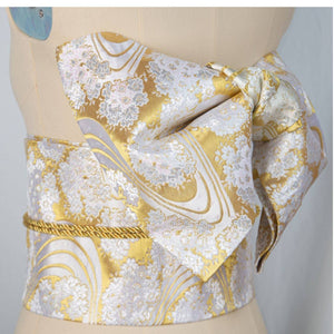 Gold and white brocade bow belt with floral patterns, styled on mannequin for traditional Japanese kimono waist seal and yukata wear.