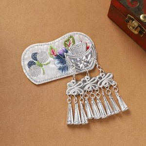 White embroidered Guizhou Miao fridge magnet with silver cone fringe, handmade ethnic decor for refrigerators or gifts.