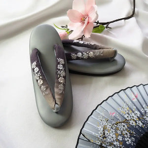 Gray Japanese kimono sandals featuring delicate white floral embroidery and gradient herringbone straps. A stylish addition to traditional outfits.