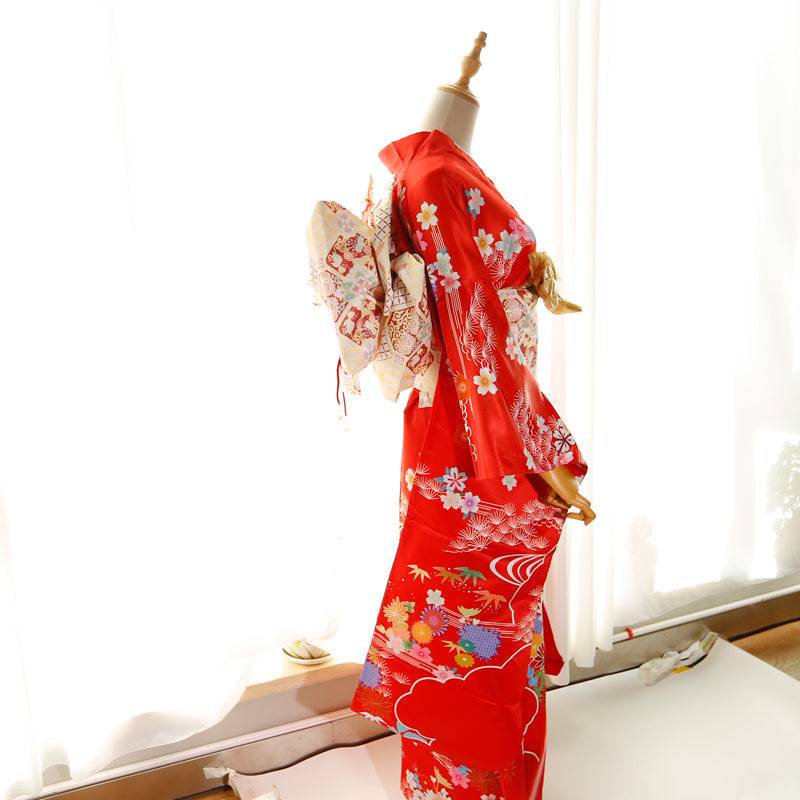 Side view of red kimono with floral prints and cream big three-leaf bow belt. Swinging sleeves and geisha-style belt bag included.