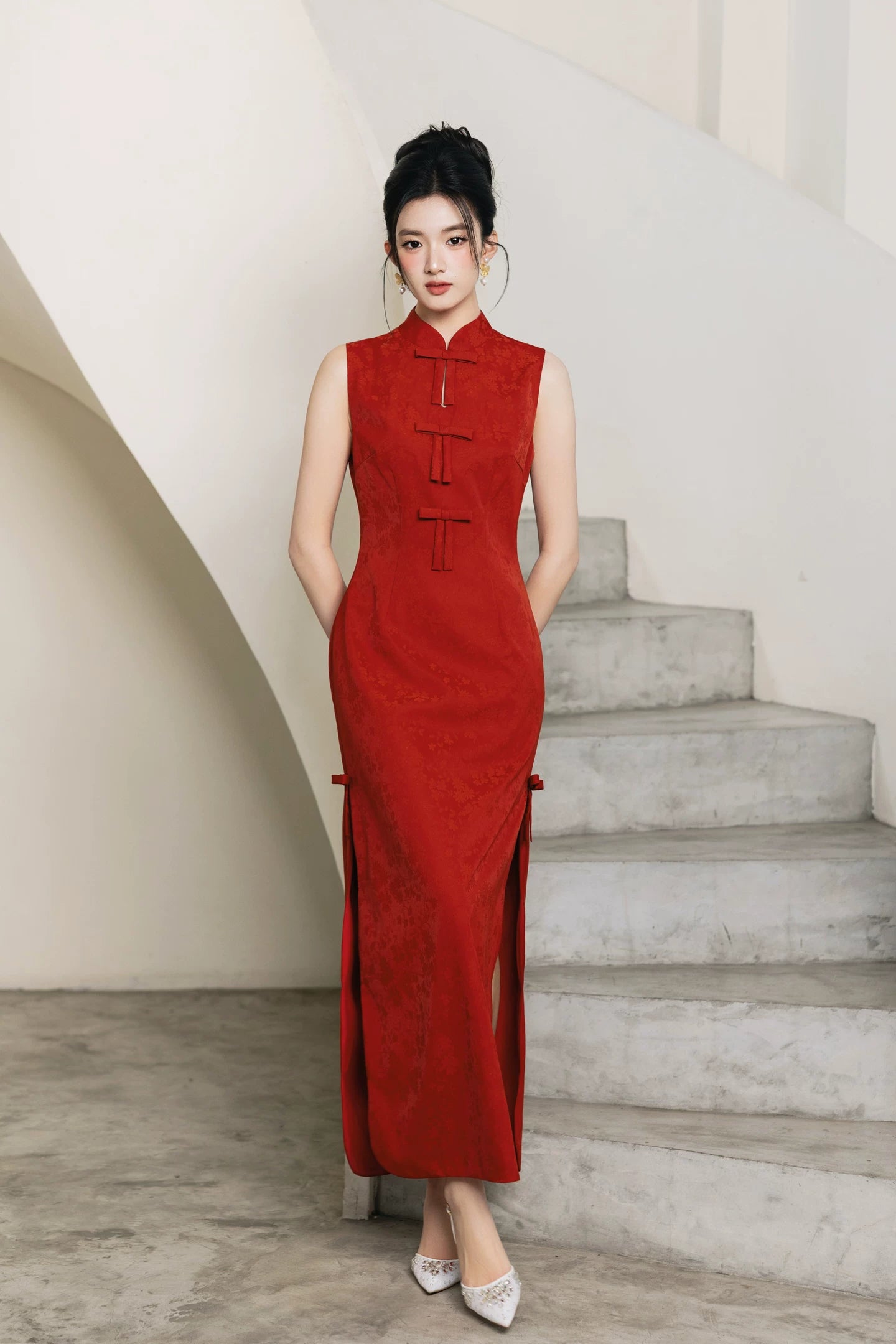 Front view of vermilion red bow bridal cheongsam on curved staircase