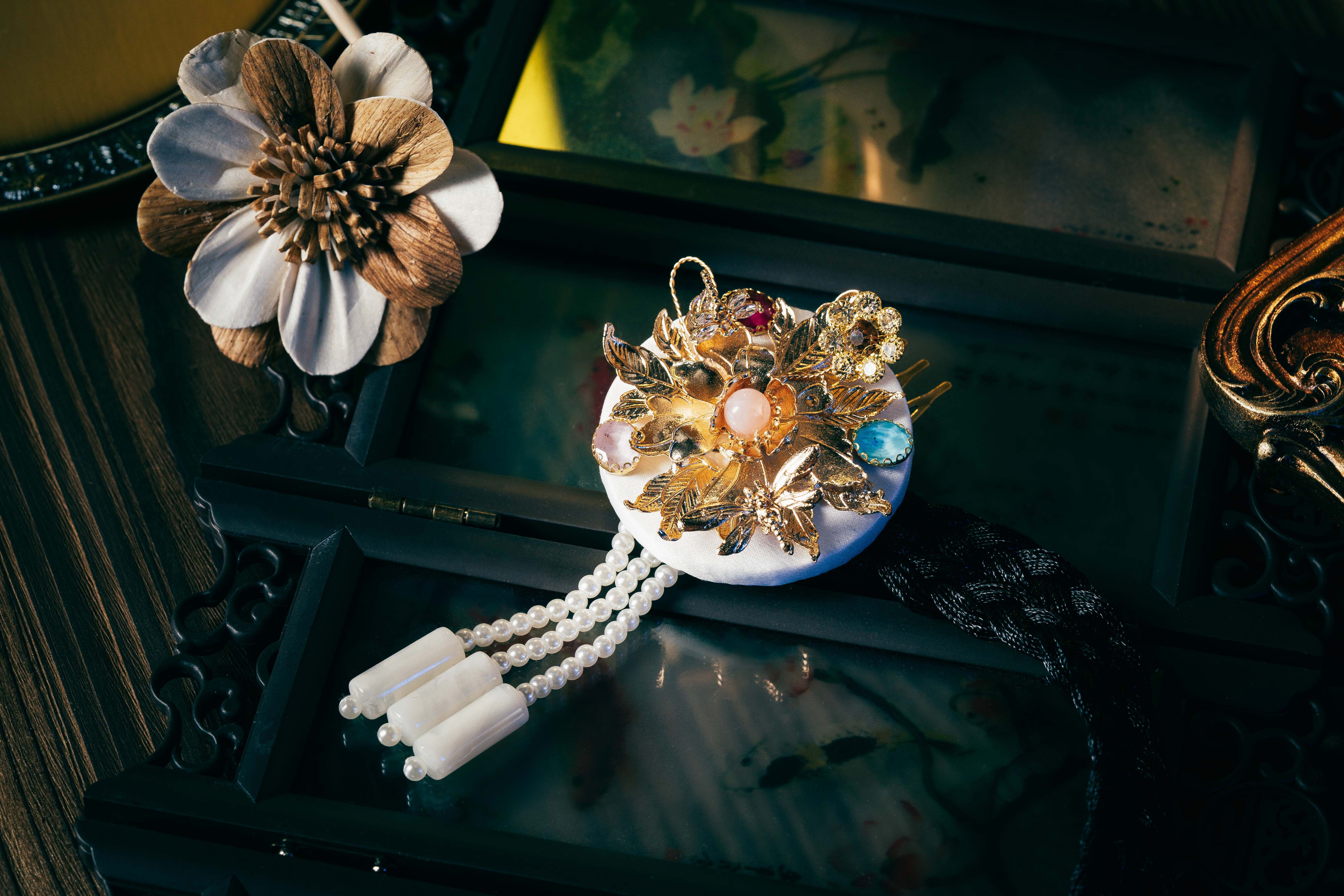 White Korean traditional ethnic headgear with gold floral design, gemstone accents, and pearl tassels, showcasing precise craftsmanship.