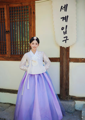 White purple Korean female high-end genuine Yanji court hanbok with traditional accessories, posed in front of wooden door and sign.