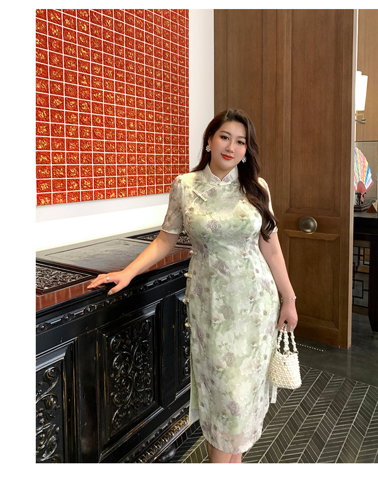 Plus size green qipao dress with traditional Chinese floral design, styled with pearl earrings and handbag for a graceful ensemble.