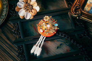 Red Korean ethnic headgear featuring gold floral ornaments, gemstone accents, and pearl strands, crafted with precision.