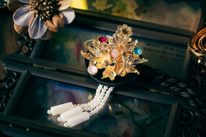Black Korean ethnic headgear with gold floral embellishments, multicolored stones, and pearl tassels, crafted with precision.