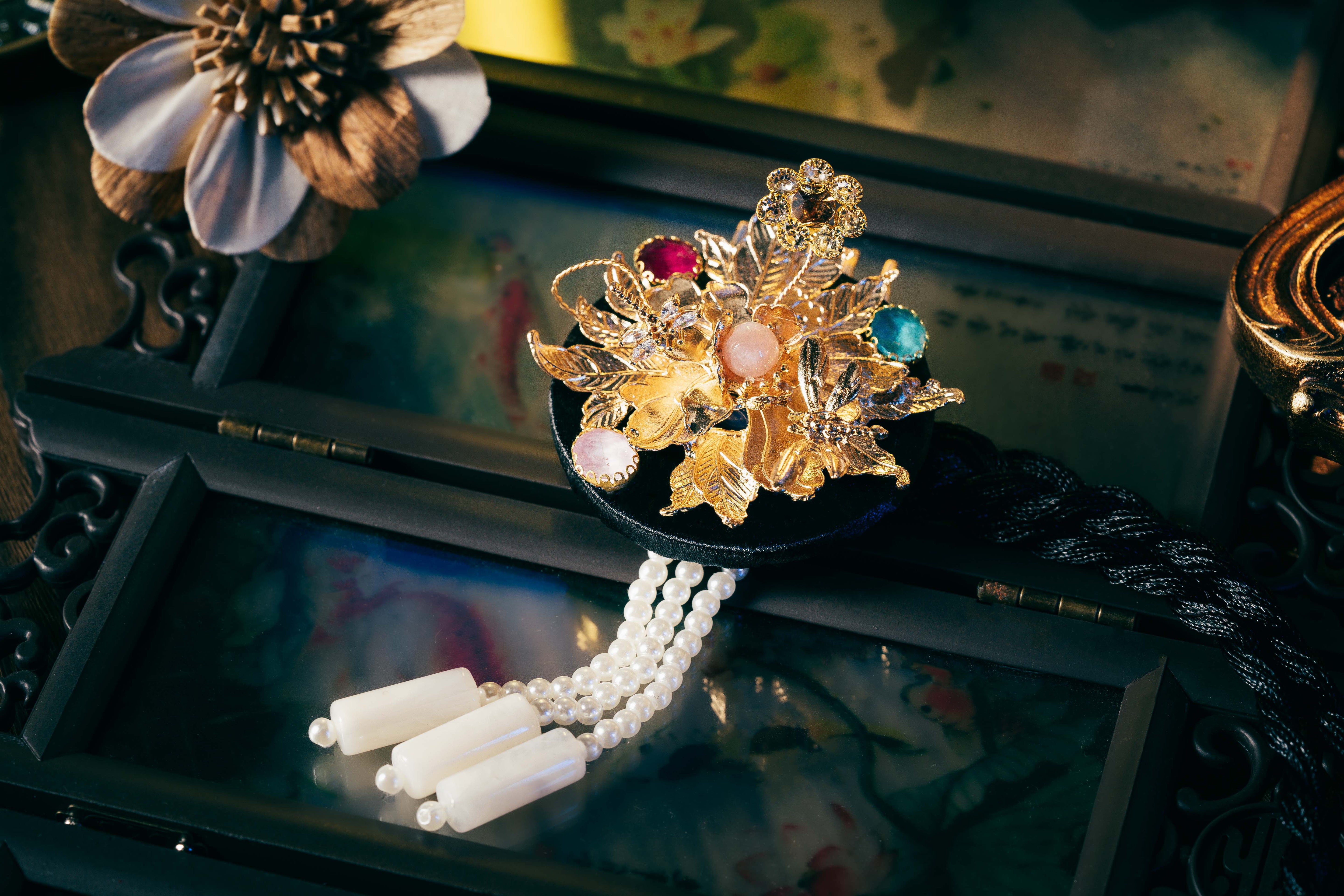 Black Korean ethnic headgear with gold floral embellishments, multicolored stones, and pearl tassels, crafted with precision.