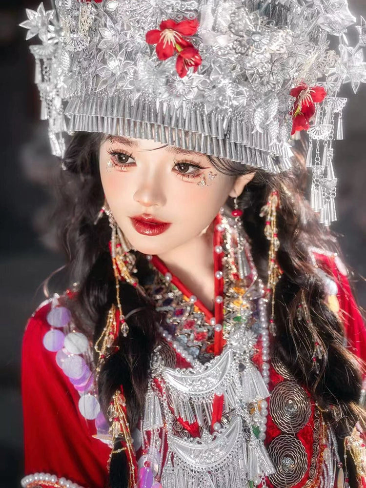 Detailed shot of ornate silver headwear and embroidery on red Miao wedding dress, highlighting traditional Chinese ethnic fashion.