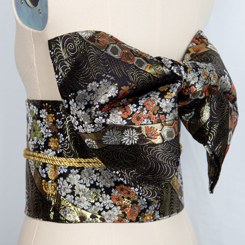 Black and gold floral brocade kimono waist seal with a large bow, perfect for enhancing yukata outfits during cultural events or photo shoots.