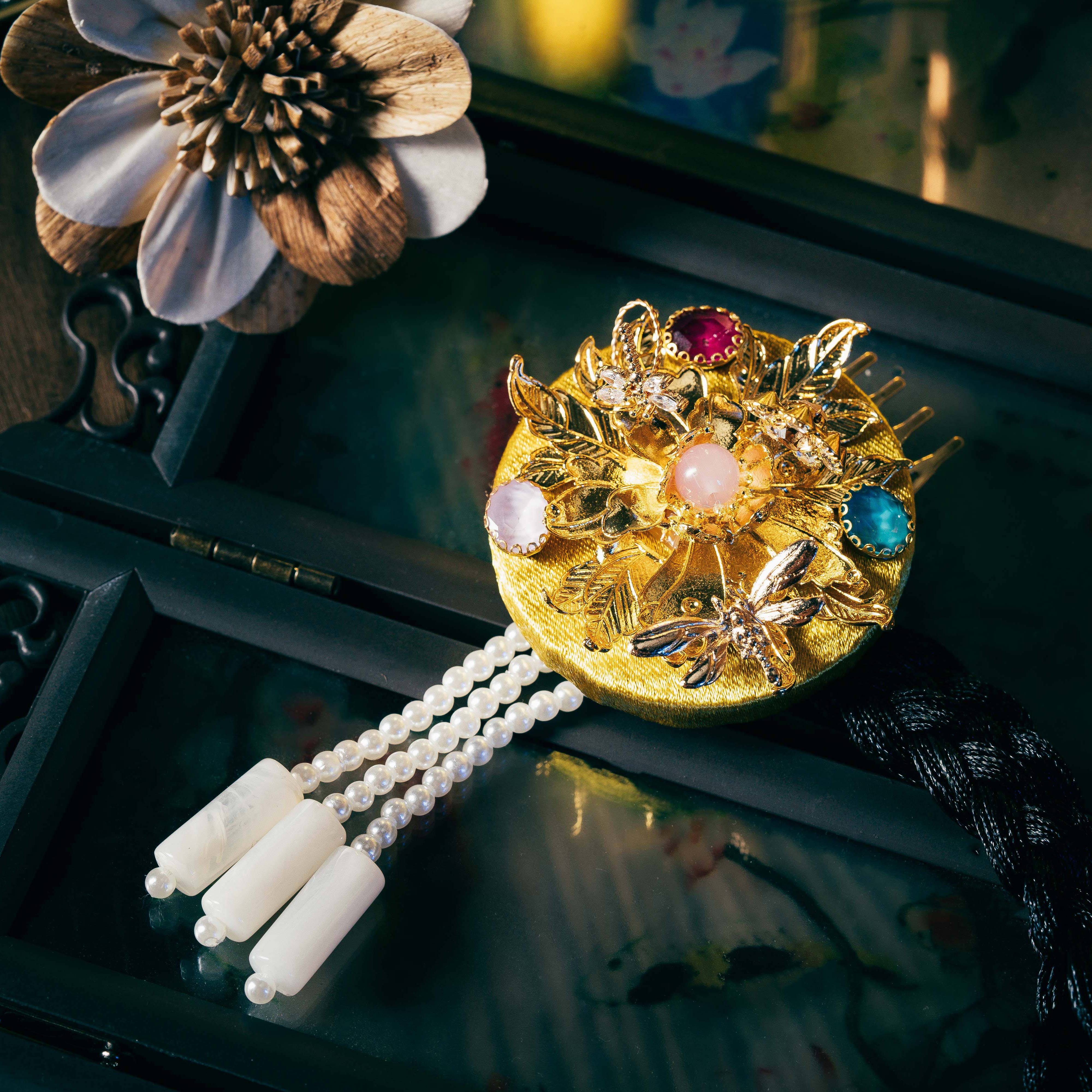 Korean traditional ethnic headgear with gold floral design, gemstone accents, and pearl tassels, showcasing precise cutting process.