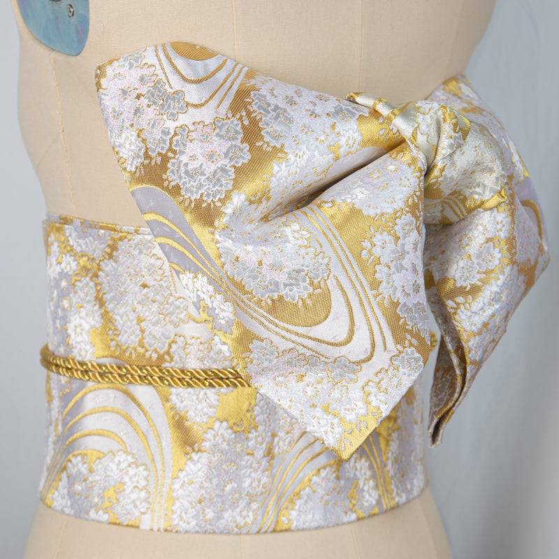Elegant gold and white Japanese yukata belt with brocade bow, ideal for enhancing traditional kimono outfits for events or photography.