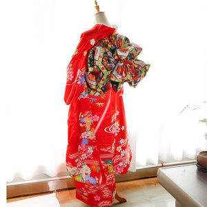 Back view of red kimono with swinging sleeves and large floral-patterned three-leaf bow belt. Traditional geisha-style belt design.