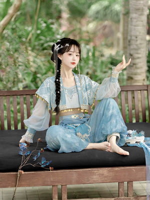 Seated model in blue Hanfu Princess Jasmine suit by 【Cloud Traveler】, styled with traditional accessories in a tropical garden.