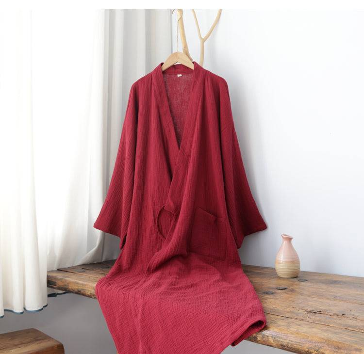 Red Zen-style cotton robe draped on a wooden bench, designed for summer comfort with a loose Hanfu silhouette and soft texture.