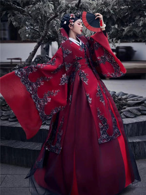 Red traditional Korean bridal gown with decorative patterns, garden setting
