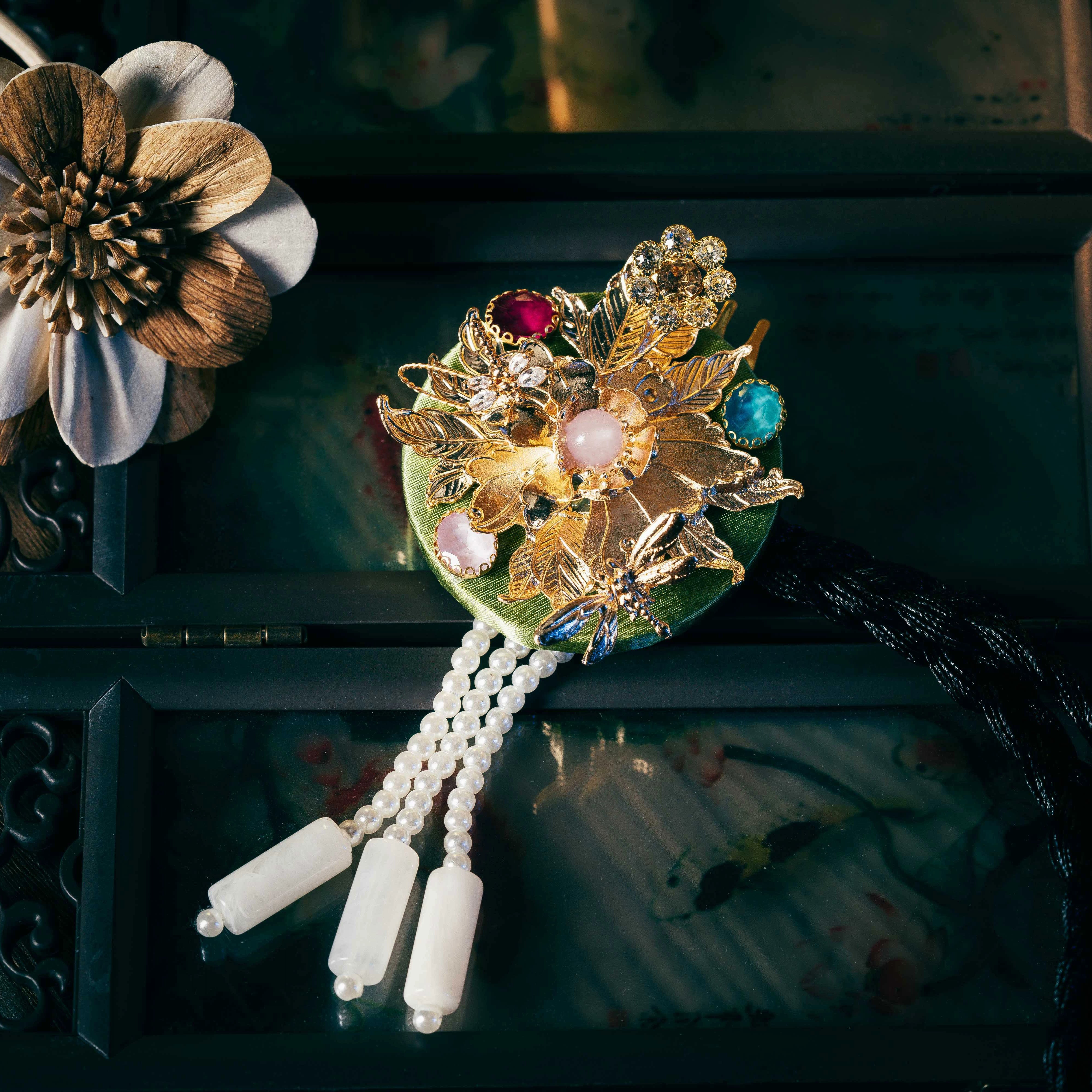 Green Korean traditional headgear with gold floral embellishments, gemstone accents, and pearl tassels, crafted with precision.