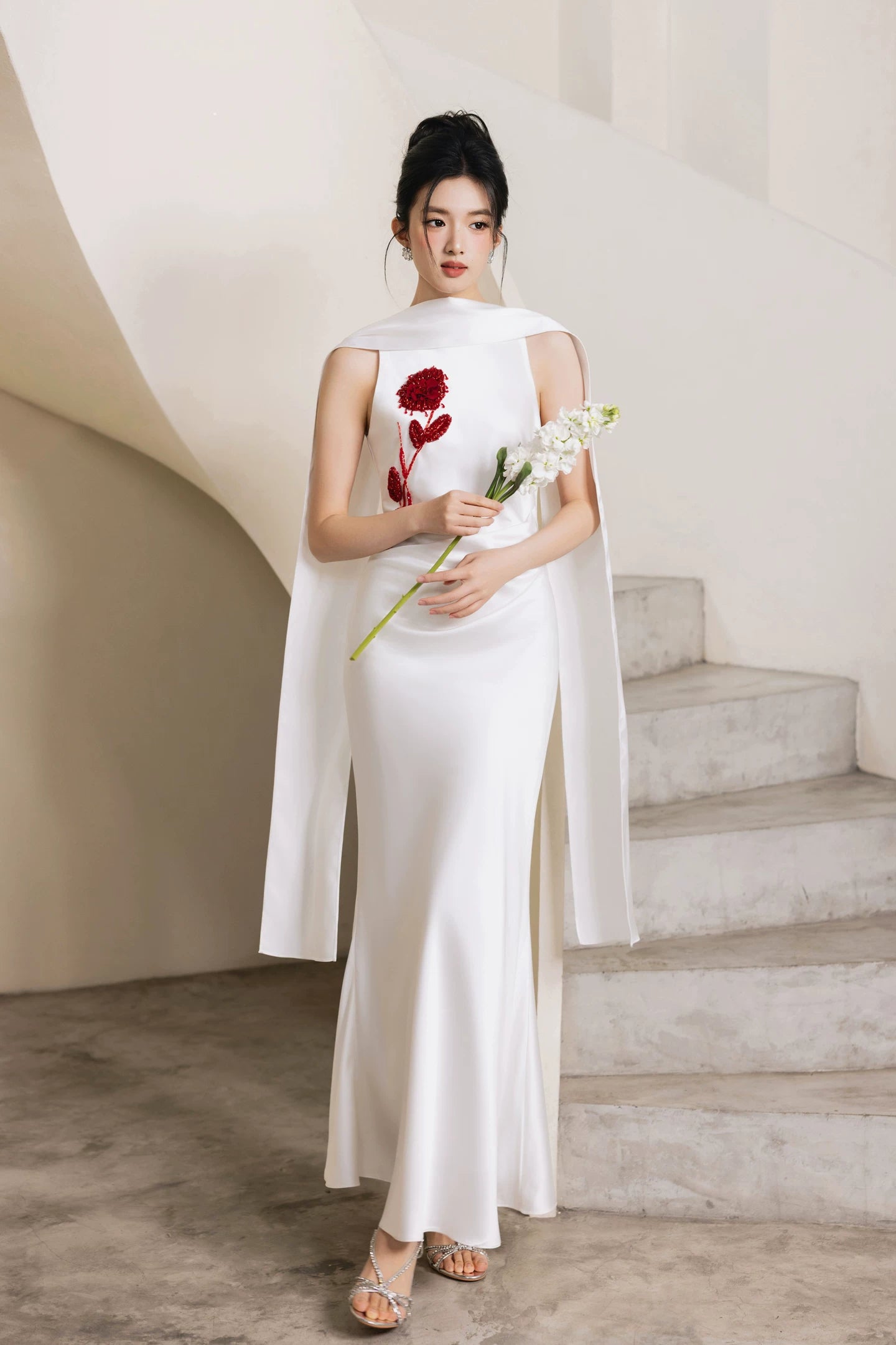 White hand-beaded column evening gown held with fresh flowers