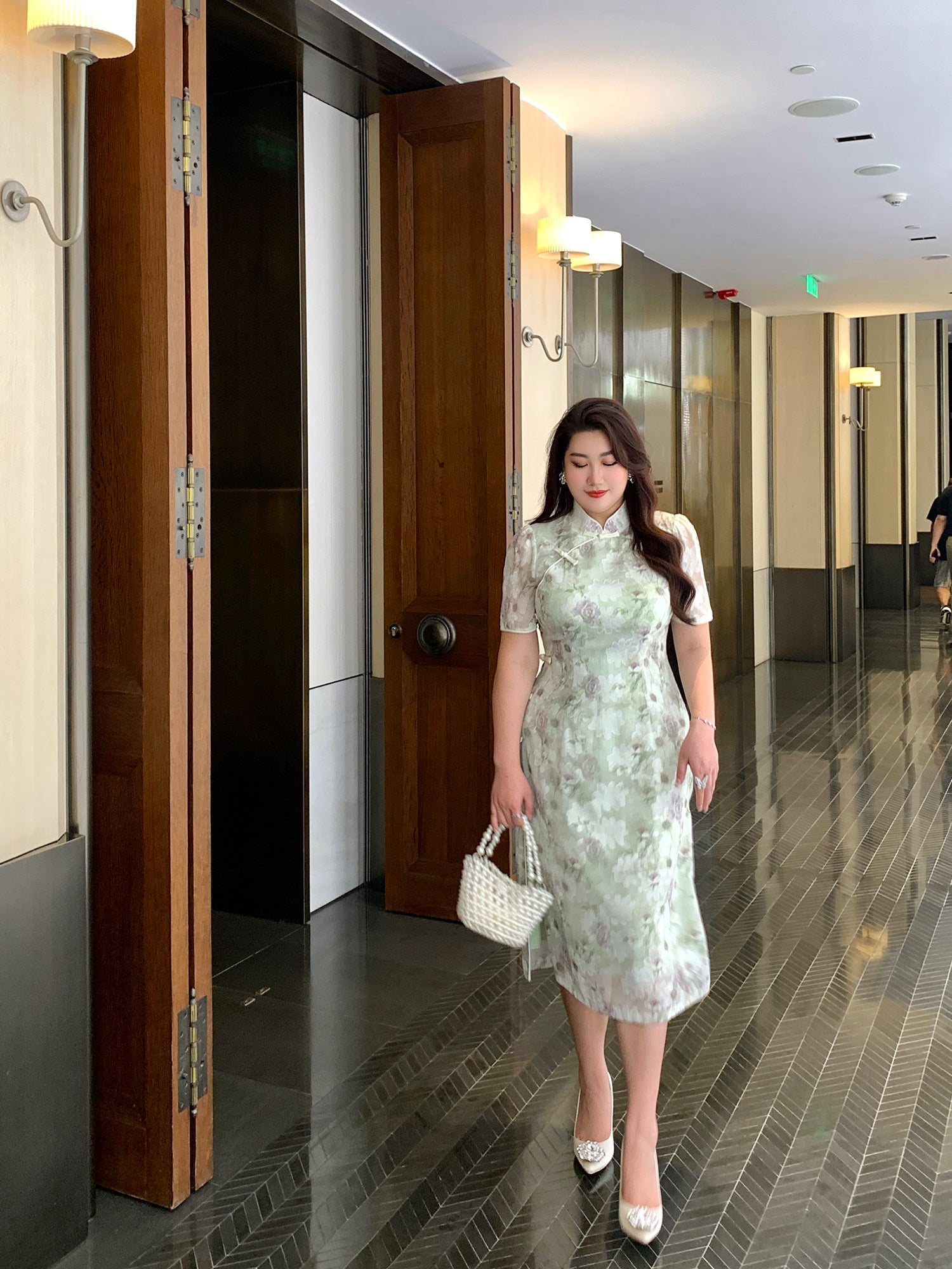 Elegant plus size green qipao dress with floral lace overlay, worn with white heels and pearl handbag, ideal for modern Chinese fashion.
