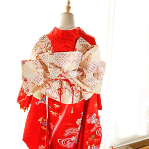 Back view of red kimono with swinging sleeves and cream floral big three-leaf bow belt. Geisha-style belt adds cultural elegance.