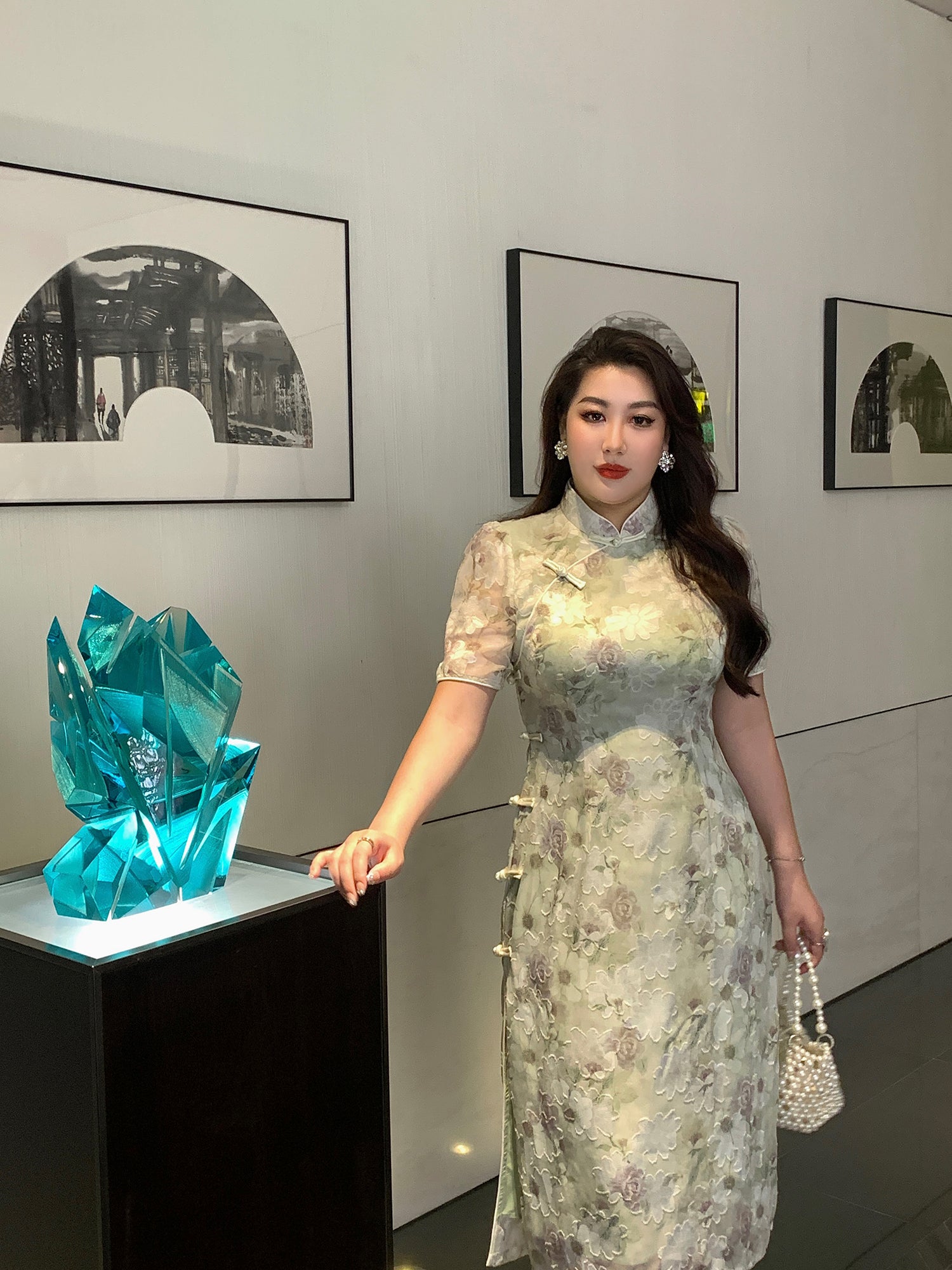 Green plus size cheongsam featuring traditional mandarin collar and floral embroidery, styled with pearl accessories for a chic modern look.