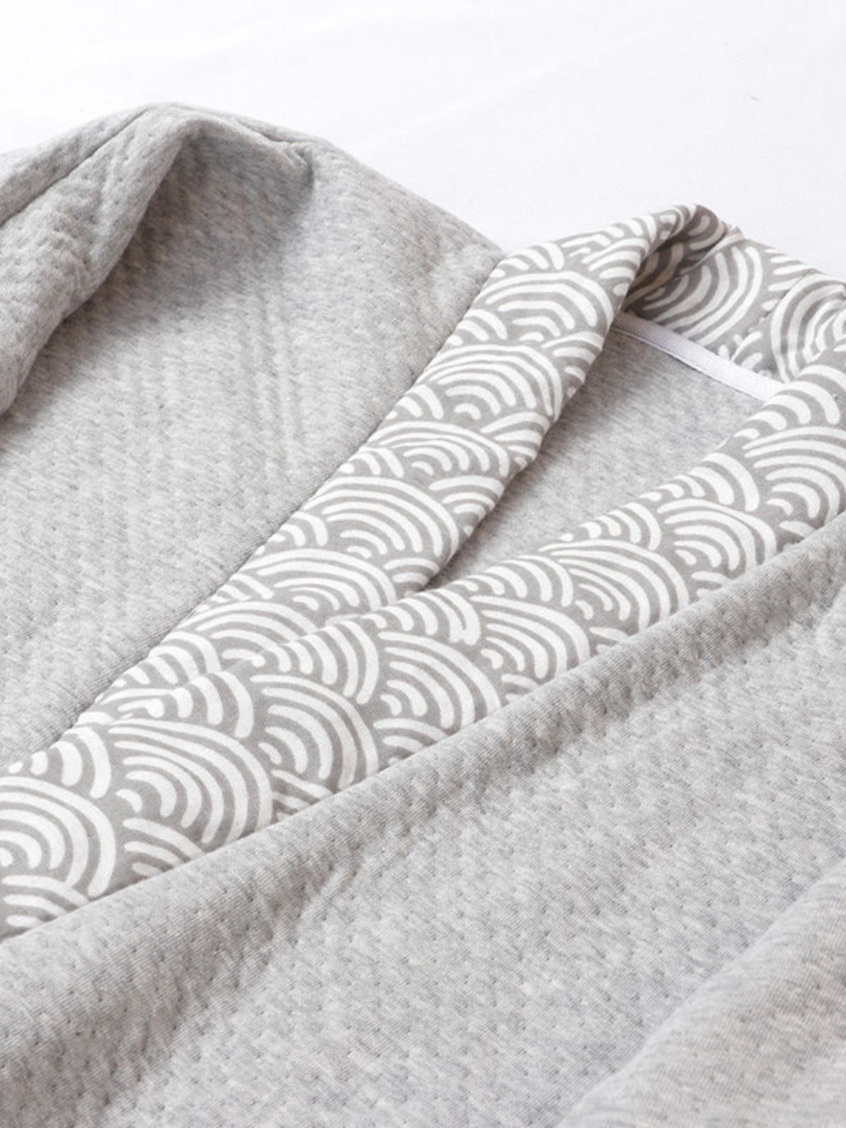Close-up of gray Hanfu loungewear collar with traditional wave-pattern trim, showcasing soft quilted fabric texture.