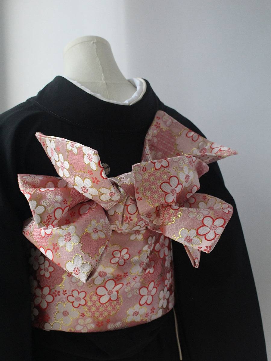 Kimono brocade waist seal in pink floral brocade with oversized bow, worn over black kimono. Elegant 120cm styling accessory.