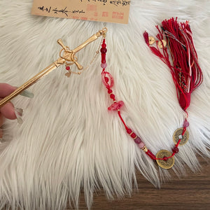 Close-up of New Chinese style sword spike tassel hairpin with red beads, gold sword pin, and traditional coin charms on white fur.