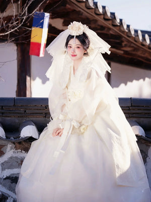 Whole white Korean traditional high-end wedding dress princess Hanbok styled for photography, featuring floral headpiece and layered silk fabric.