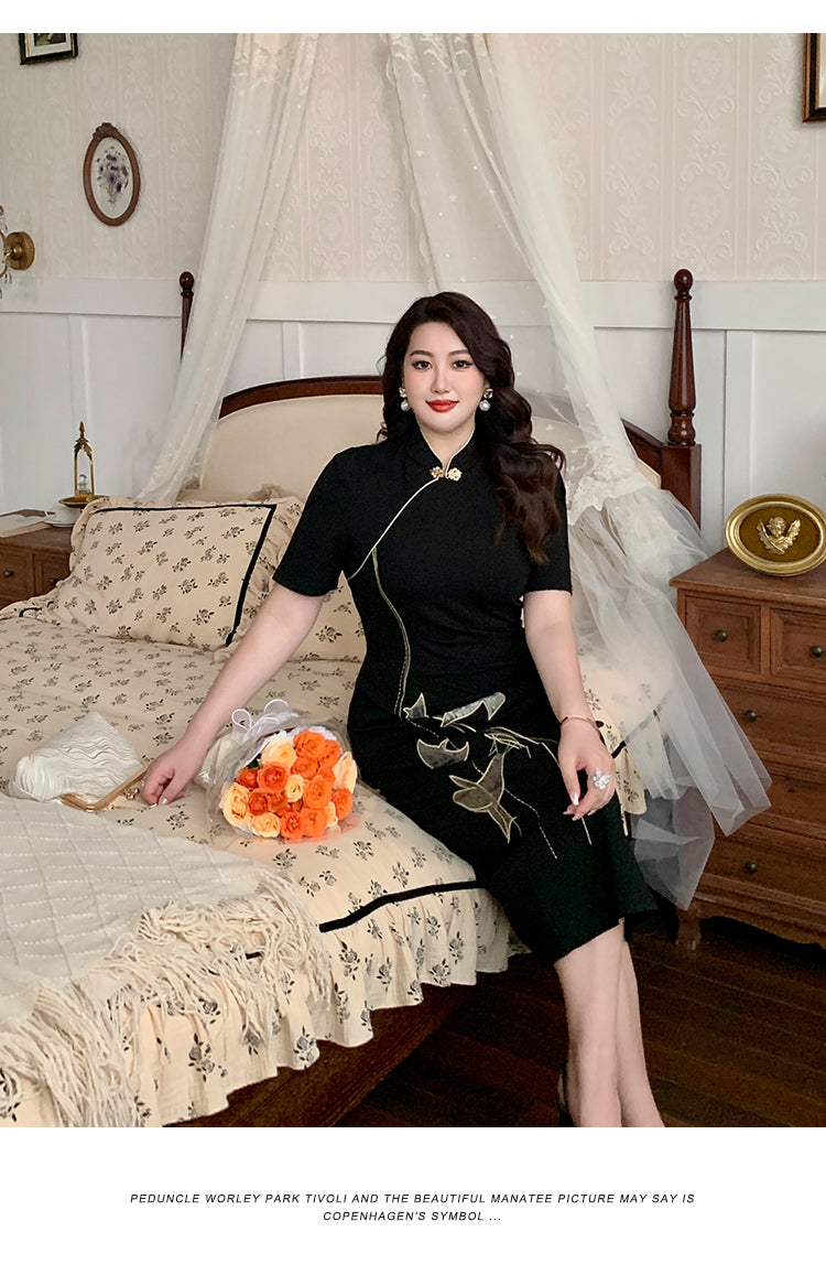 Elegant black plus size cheongsam dress with gold bird embroidery, styled in a cozy vintage bedroom with floral accents.