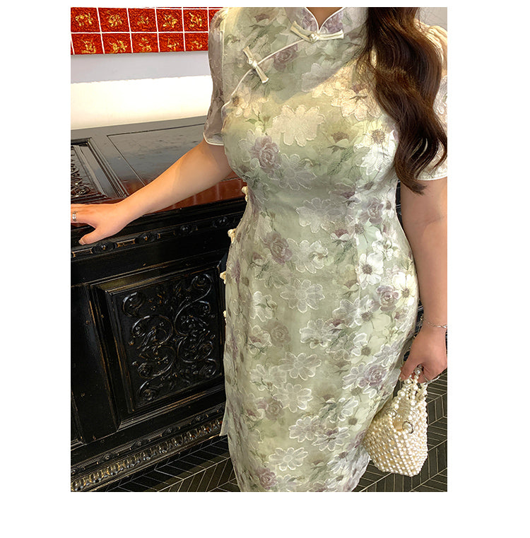 Close-up of green plus size cheongsam showing intricate floral embroidery and side knot button details, perfect for elegant occasions.