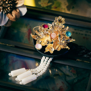 Black Korean ethnic headgear with gold floral embellishments, multicolored stones, and pearl tassels, crafted with precision.