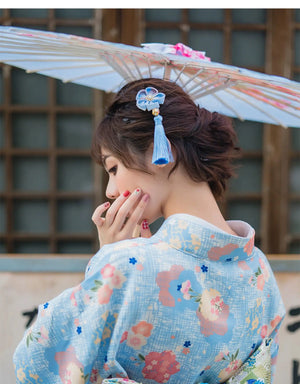Close-up of a woman in a light blue floral kimono yukata with a decorative hair accessory. A delicate and elegant Japanese-inspired dress.