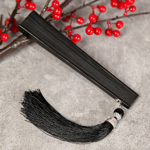 Closed black bamboo folding fan with black tassel, perfect for Hanfu or traditional Chinese dance. Compact and elegant design.