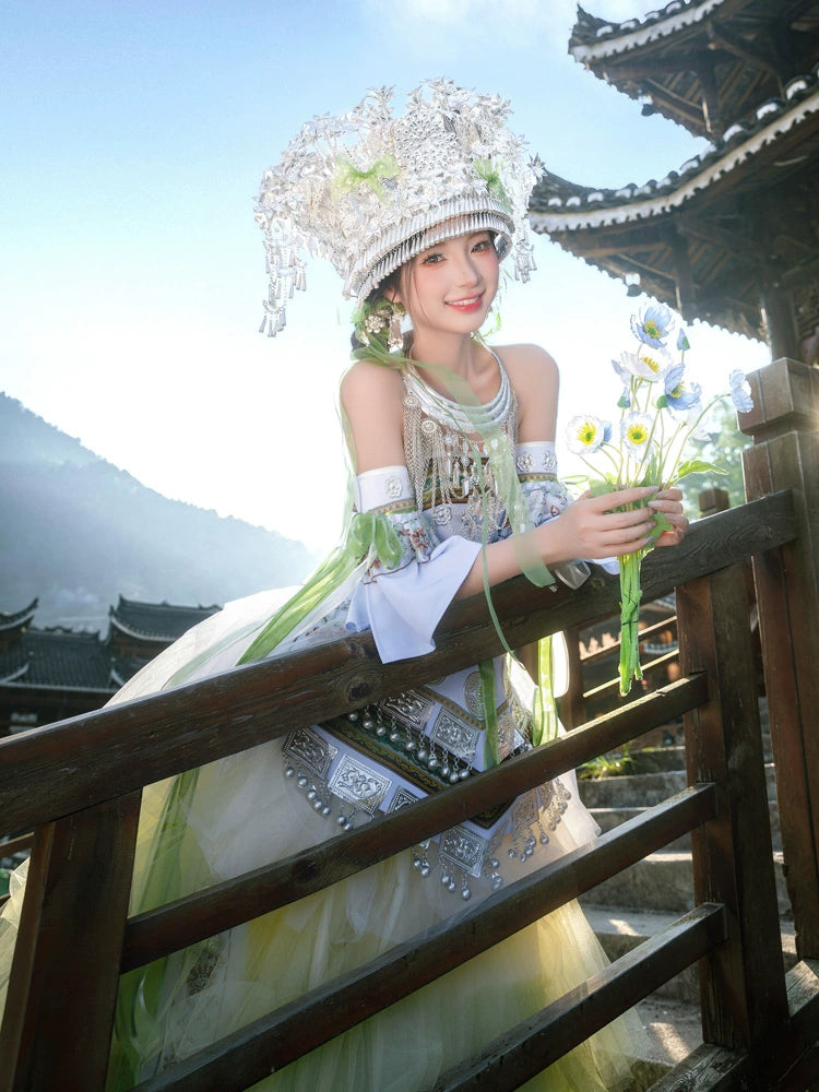 Traditional Pink Miao Clothing Women's Summer Cake Green Dress with silver headwear and green tulle skirt, posed on wooden balcony.