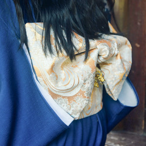 Gold and white brocade bow belt styled with navy kimono, ideal for traditional Japanese yukata waist styling and cultural photography.