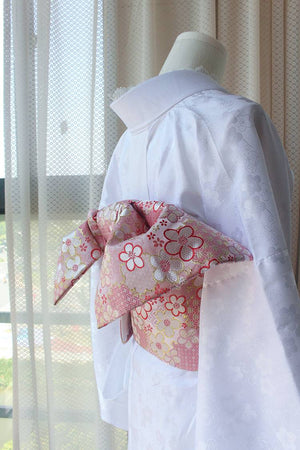 Angled view of pink floral brocade kimono waist seal with bow, styled on white kimono. 120cm reversible cotton canvas design.