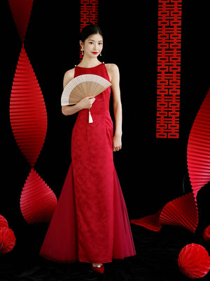 Model in red cheongsam wedding dress holding a fan, designed for elegant bridal engagement or toasting ceremonies.