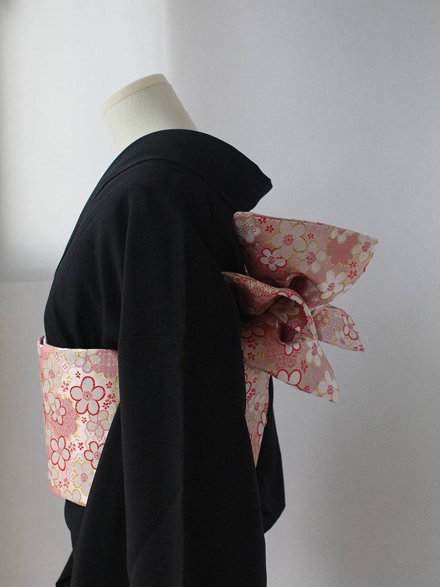 Side view of pink floral kimono brocade waist seal with bow, styled on black kimono. 120cm reversible cotton canvas design.