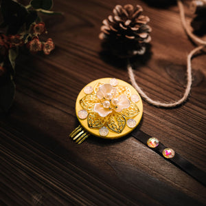 Yellow Korean traditional ethnic headgear with white pearl floral design and glittering accents, displayed on wood.