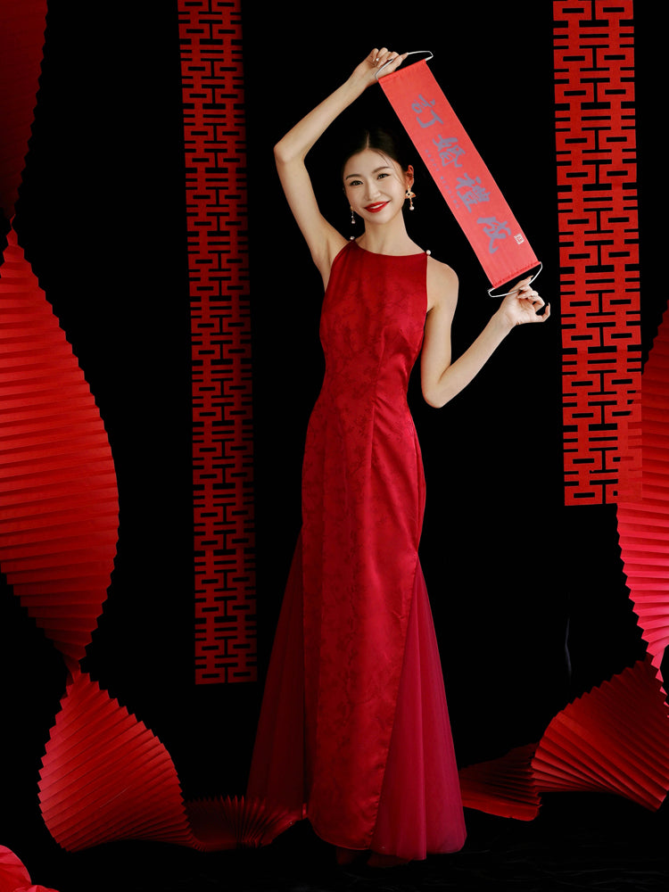 Bride in red cheongsam dress holding vertical red scroll, styled for engagement or wedding ceremonies.