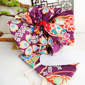 Close-up of purple kimono belt with colorful floral big three-leaf bow. Geisha-style accessory for traditional kimono outfits.