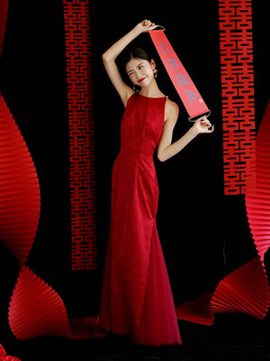 Bride in red yarn cheongsam dress with fan, standing in soft-lit setting, ideal for wedding or engagement.